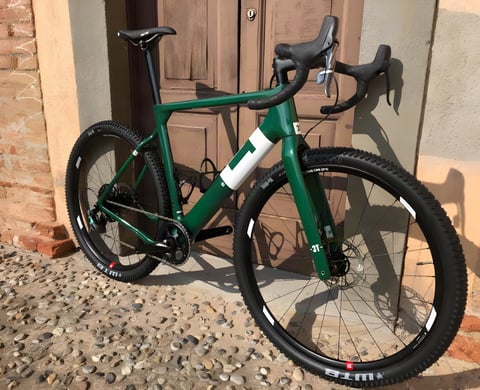 Limited edition Team Force Green 3T Exploro Flatmount gravel bike leaning against a wooden door.