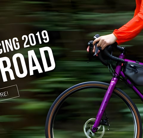 Salsa 2019 All-Road launch banner with a rider in an orange jacket on a purple drop-bar bike with a frame bag.