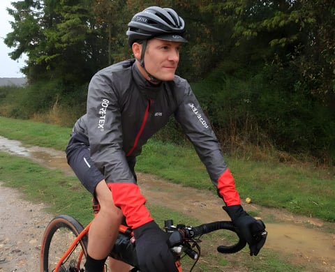 Rider in the Gore C5 Gore-Tex Shakedry 1985 Viz jacket on a wet gravel track, red cuffs and logos visible.