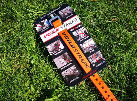 Orange 20-inch Voile Strap on its retail card, lying on grass.