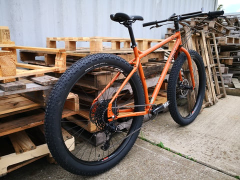 Rear three-quarter view of the Surly ECR showing its Knard 29+ tyre, orange frame and swept-bar cockpit.