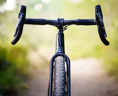 3T Superghiaia Team Stealth flared bars with SRAM Force shifters, head-on on a gravel bike with a blurred trail behind.