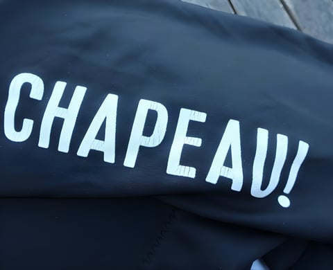 Chapeau Club Thermal Bibtight with the white Chapeau! logo cracking and peeling on a black leg.