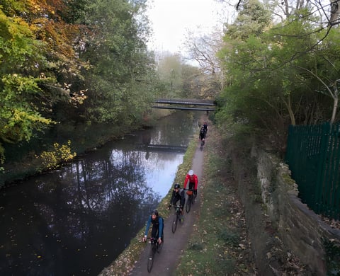 Riders on gravel bikes follow a canal towpath on the Rapha Prestige Manchester ride.