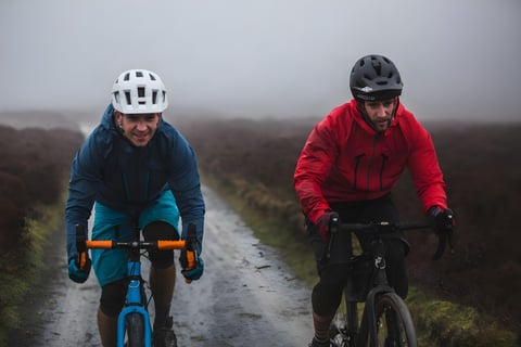 Two riders on gravel bikes ride a wet, misty moorland track in the Shropshire Hills during the Orange RX9 film.