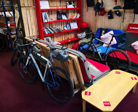 Sonder Camino AL with Alpkit waterproof luggage propped against a bench in the staff café at Alpkit HQ, Nottingham.