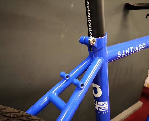 Seat tube junction and seatstay bosses of the blue Sonder Santiago steel frame, with Santiago decal on the top tube.