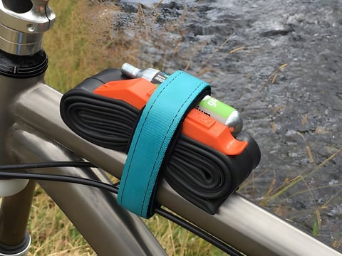 Turquoise Backcountry Research Mutherload strap holding a spare inner tube, tyre levers and a CO2 cartridge on a top tube.