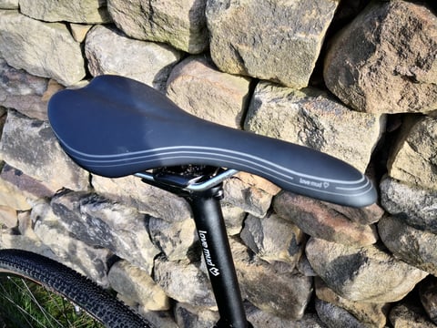 Love Mud Abode saddle in black with grey stripes, mounted on the Sonder Camino AL's black seatpost.