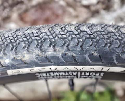 Close-up of the Teravail Cannonball 650b gravel tyre tread and sidewall logo, with dust in the diamond-shaped lugs.