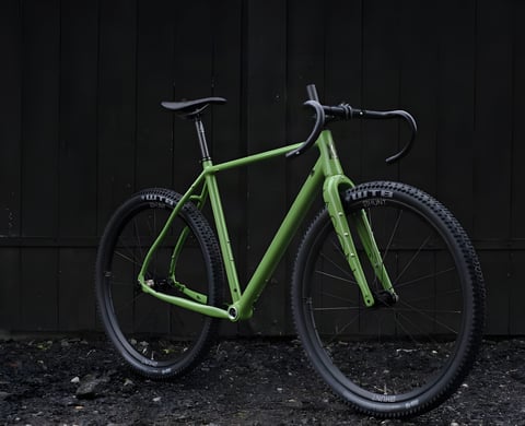 Mason Bokeh 2 in Filter Green with WTB tyres on Hunt wheels, leaning against a dark wooden wall.