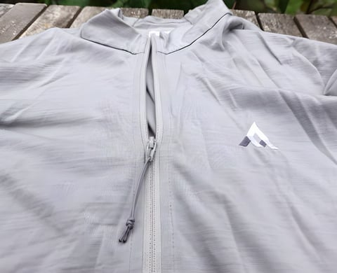 7Mesh Ashlu Merino Jersey in grey laid flat, showing the full-length zip with string toggle and chest logo.