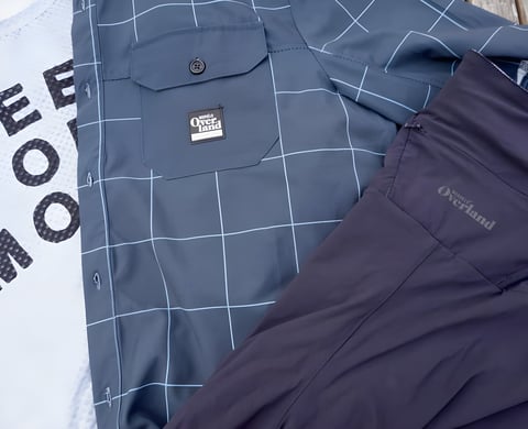 Morvelo Overland shirt with pocket badge, laid on a grey base layer and navy shorts.