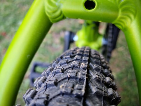 Knobbly Kenda tyre sitting between the green seatstays of the Bombtrack Beyond Junior, showing clearance.