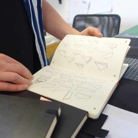 Straight Cut sketchbook filled with small drawings of bag panel shapes, held open by Ross O'Reilly.