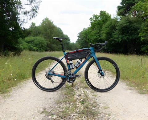 Wilier Jena Ultegra gravel bike in teal and red with a frame bag, on a forest gravel track.