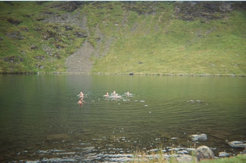 Riders swim in a cold Lake District tarn, one of the wild swim spots marked on the weekender maps.