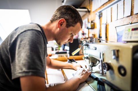 Detour Studio maker stitching a bikepacking bag at a sewing machine, one of the small makers in this gift guide.