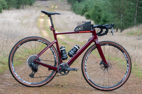 Burgundy Cervelo Aspero gravel racer with Scope O2 wheels and WTB Byway tyres on a forest track, the Dirty Reiver build.