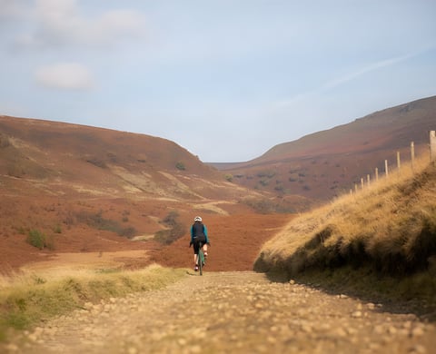 Gravel rider on a stony track through red-brown hills, promoting the Sonder Winter Gravel Series.