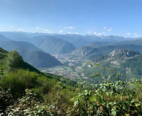 View down a green Pyrenees valley from a hillside on the Further bikepacking race in France.