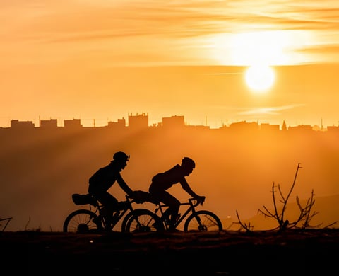 Axel Carion and Jonas Deichmann silhouetted against a sunset on their Jordan Bike Trail record ride.