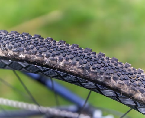 Mud-flecked WTB Raddler gravel tyre tread seen close up, with the knobbly side lugs in sharp focus.