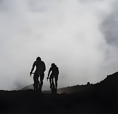 Two riders in silhouette climb a ridge into low cloud on Maui, Hawaii, from Kona's Into the Clouds film.
