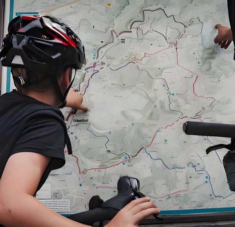 Lubin, in a helmet, traces a route on a trail map with his father before their Bombtrack Beyond Junior bikepacking trip.