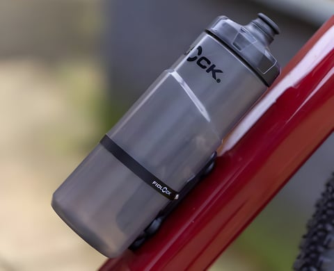 Fidlock TWIST 600 bottle held magnetically on the down tube of a red bike frame.