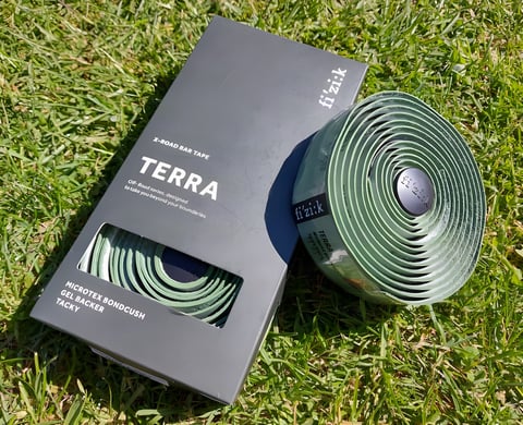 Fizik Terra Microtex Bondcush Tacky bar tape in green, with its box, lying on grass.