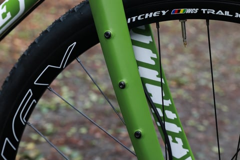 Mounting bolts on a leg of the green Ritchey Outback V2 carbon adventure fork, beside a Ritchey WCS Trail rim.