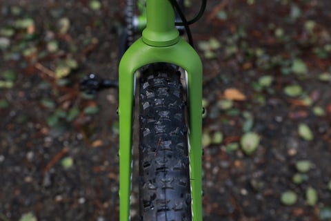 Knobbly front tyre inside the green Ritchey Outback V2 carbon fork, seen from above to show the clearance.