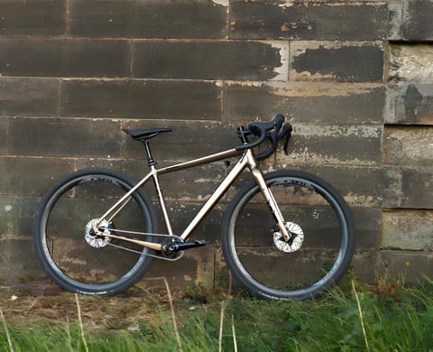Gold Salsa Stormchaser singlespeed gravel bike leaning against a stone wall, built up by Keep Pedalling.