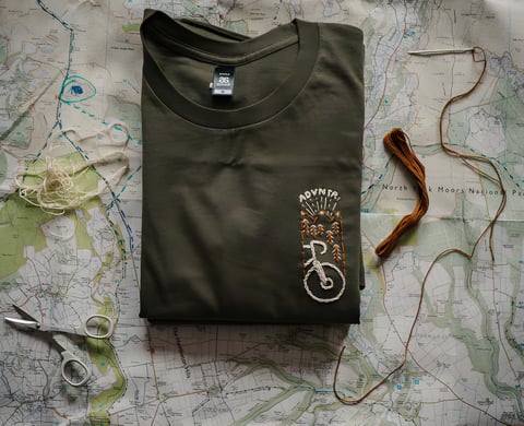Folded army green Get Wild x ADVNTR t-shirt with a hand-embroidered bike motif, on a North York Moors map.