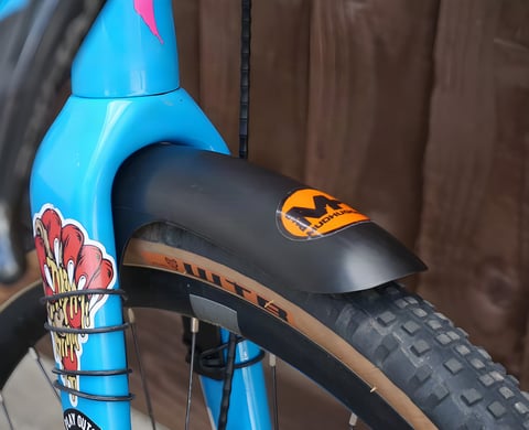 Mudhugger Gravelhugger front mudguard fitted to the fork of a blue gravel bike with a tan-wall tyre.