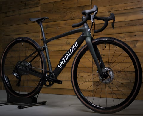Specialized Diverge 2020 gravel bike in dark green with Shimano GRX and tan-wall tyres against a wood-panelled wall.