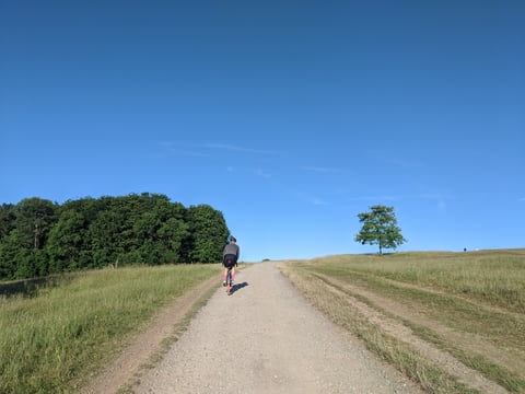 Rider climbs a gravel track under blue sky near Bristol during the Dirty Kanzelled 100-mile ride.