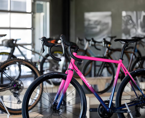 Pink-to-navy fade custom bike with drop bars on show at the ENVE Builder Round-Up, with other builds behind.