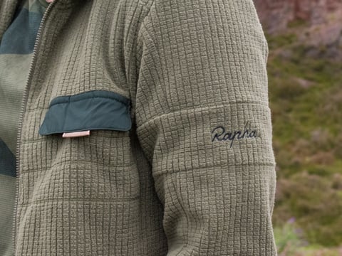 Rapha Explore Technical Hoodie in olive grid fleece, close-up of the sleeve logo and chest pocket, from the range on test.