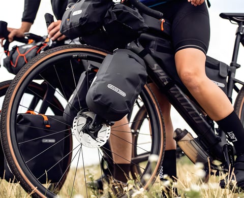 New Ortlieb fork packs mounted either side of a gravel bike's front wheel, alongside other Ortlieb bikepacking bags.