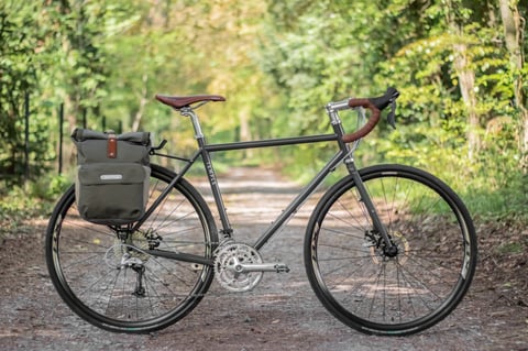 Temple Adventure Disc 3 steel touring bike with triple chainring and a pannier, on a wooded gravel track.