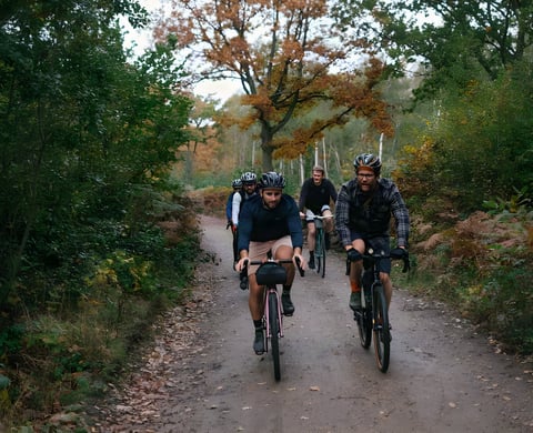 Group of riders on gravel bikes on a leaf-strewn woodland track during the Brother Cycles Kent gravel ride recce.