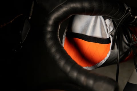 Wiz Viz handlebar bag in reflective fabric and fluro orange, viewed past the bar tape of a drop handlebar.