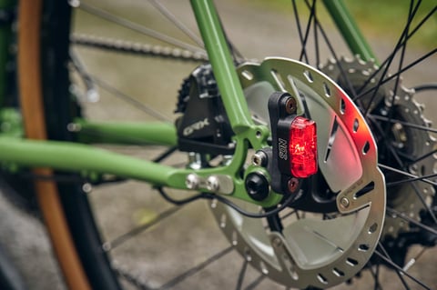 SON rear light mounted beside the rear disc rotor and GRX brake caliper on the Woodland Green Fairlight Faran 2.