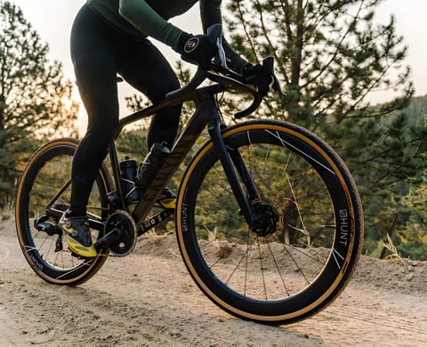 Rider on a Canyon gravel bike fitted with Hunt 42 Limitless Gravel Disc wheels and tan-wall tyres on a dirt trail.