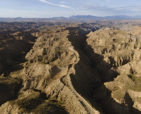 Aerial view of a gravel road winding through the eroded badlands of the Gorafe Desert, Badlands race route in Spain.