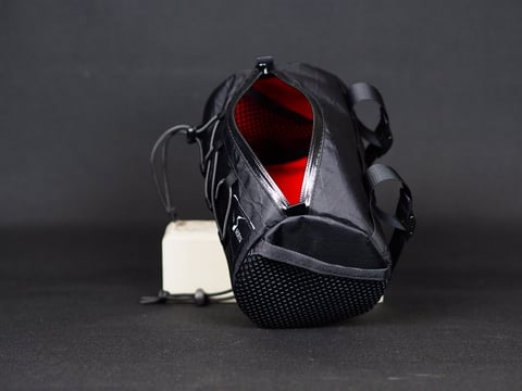Black Heron Fabrix handlebar bag unzipped to show its red lining, with a mesh end panel.