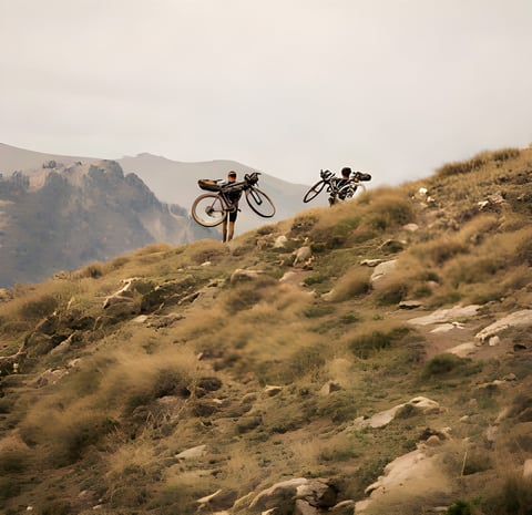 Svein Tuft and Christian Meier shoulder loaded bikes up a rocky Pyrenean hillside in the short film Connection.