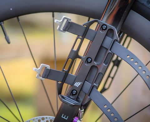 Tailfin Cargo Cage with Load Chip bolted to a fork, two black straps looped through its slots ready for a bag.